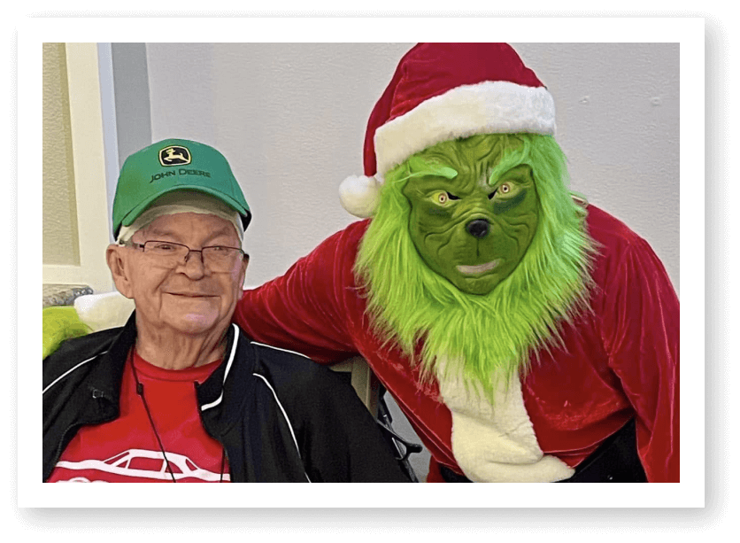 Elderly Man Posing with Costumed Character During Holiday Event at Assisted Living Facility