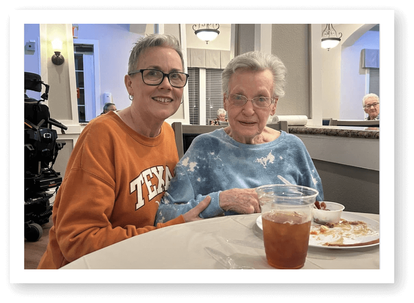Two Elderly Women Smiling Together During Meal at Assisted Living Facility