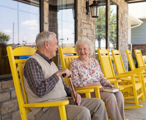 Elderly Couple Sitting in Rocking Chairs on Porch at Assisted Living Facility Elderly Couple Sitting in Rocking Chairs on Porch at Assisted Living Facility