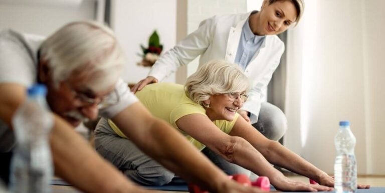 Female Nurse Guiding Elderly Stretching Exercises at Memory Care Facility