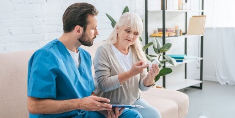 Male Nurse Reviewing Medication with Elderly Female Resident at Memory Care Facility